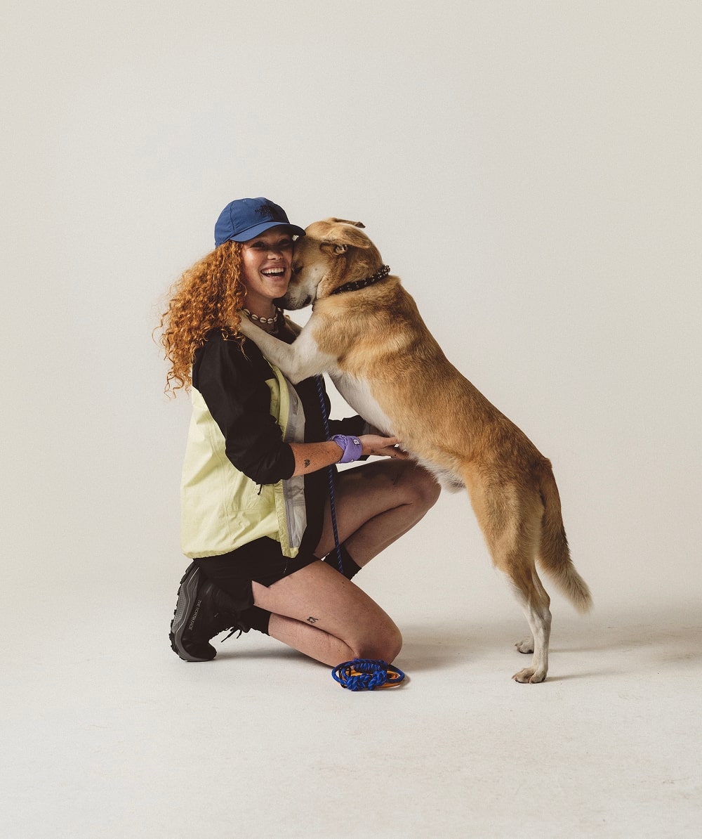 Kneeling woman wears yellow jacket.