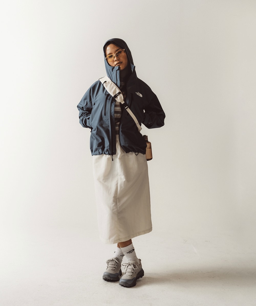 Women wearing blue rain jacket and a white skirt crossing her legs