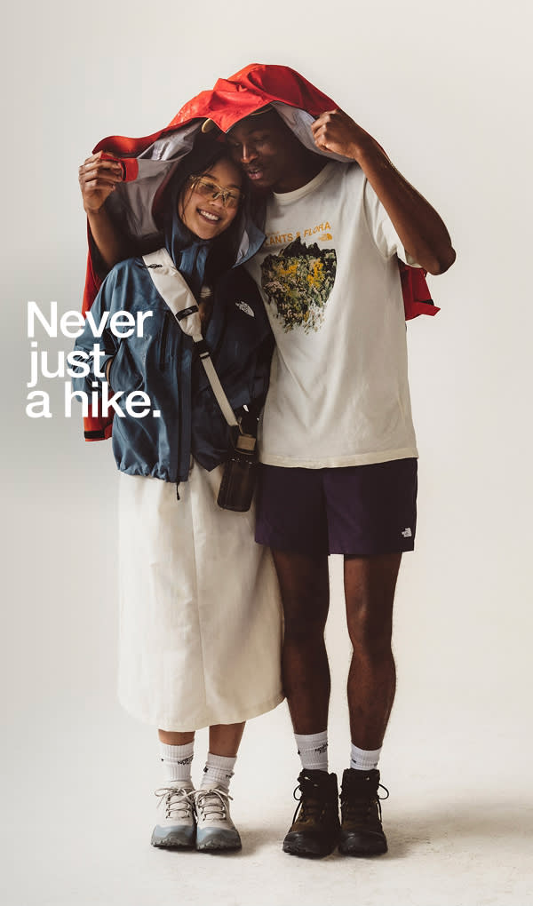 Men holding red rain jacket over woman smiling