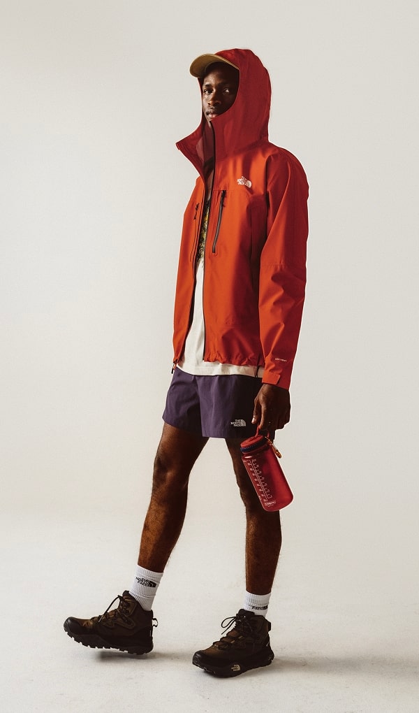 Man standing up in white background wearing red rain jacket.
