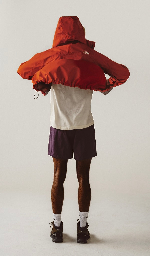 man facing away putting on a red rain jacket.