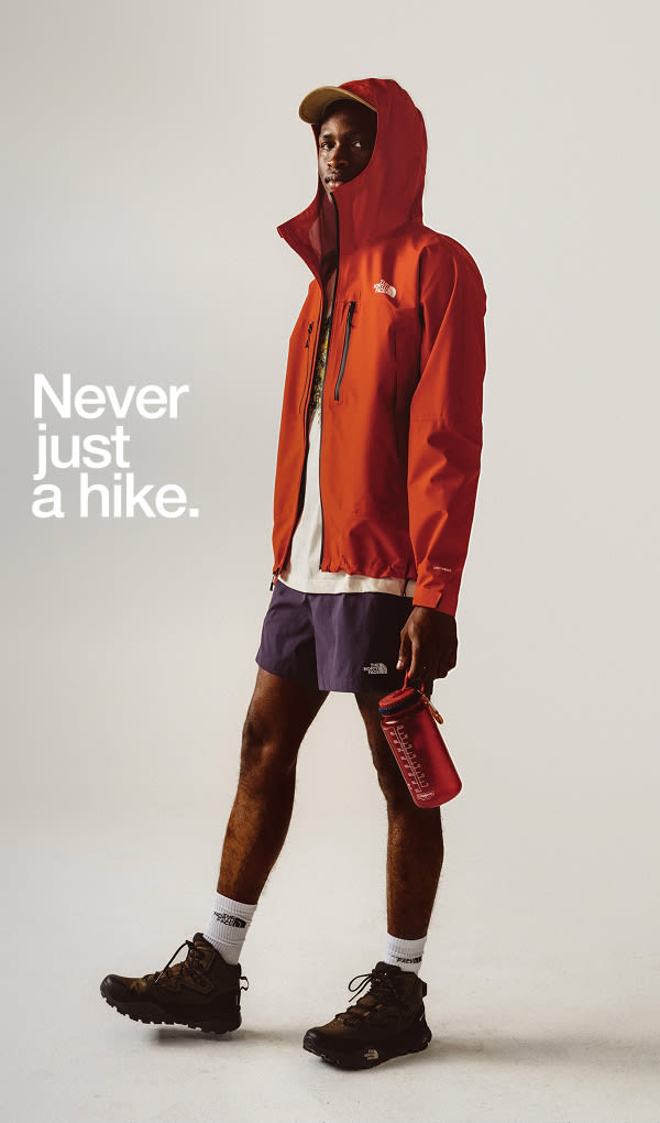 Man standing in white background wearing red rain jacket.
