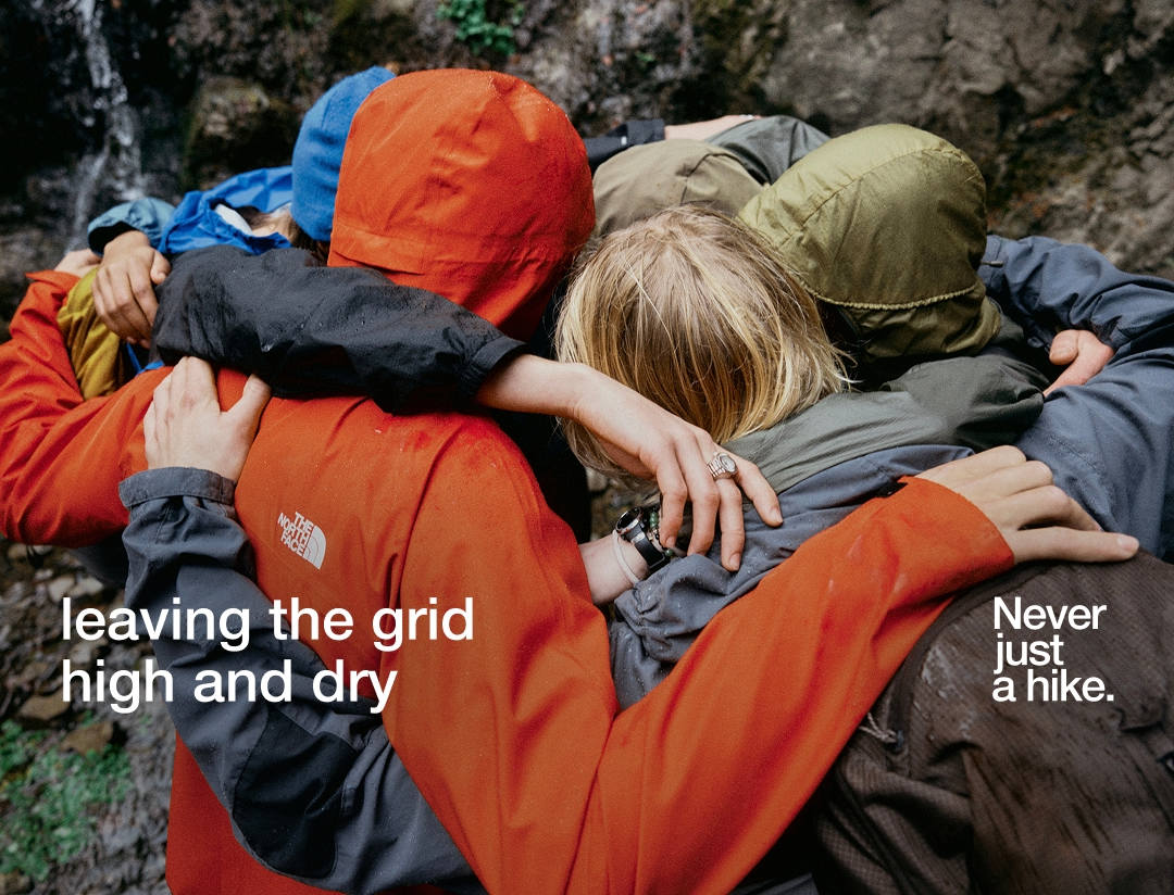 Group of hikers in rain jackets hugging.