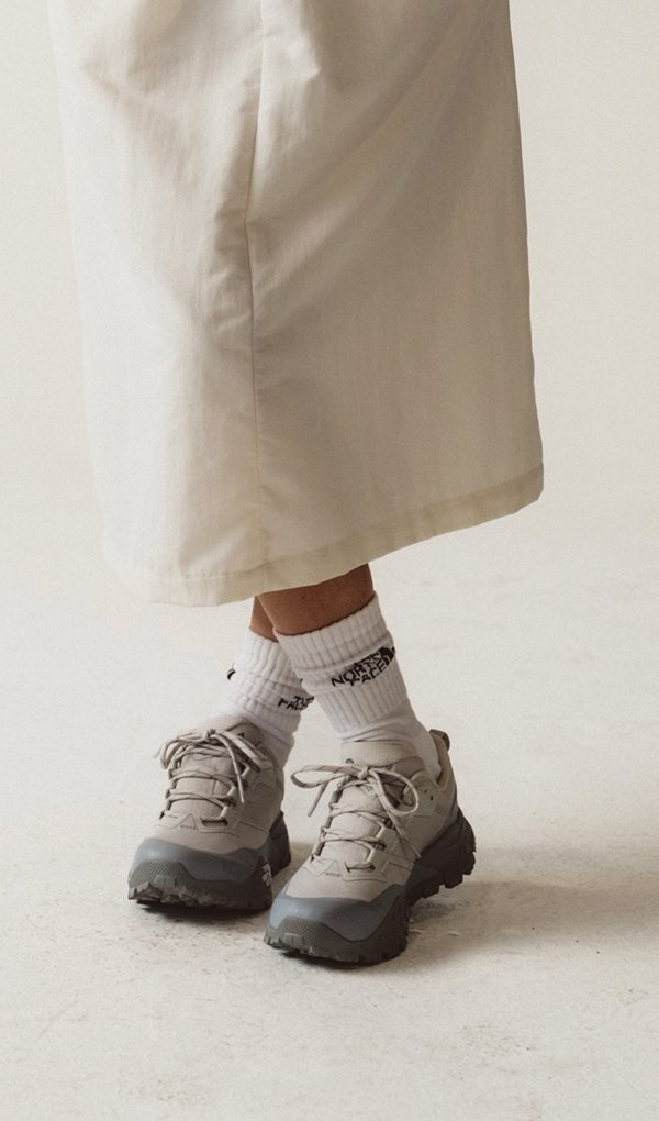 Close up of woman wearing white skirt and north face socks and shoes. 