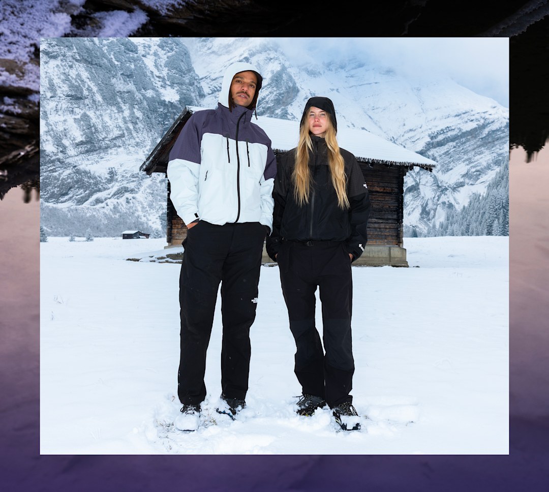 Man and woman in jackets face mountain. 