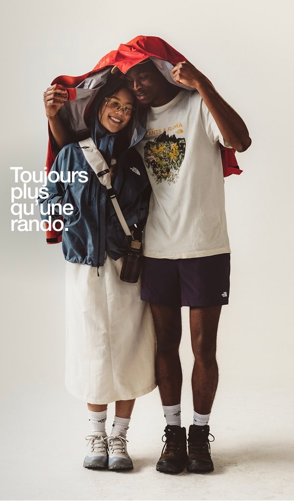 Des hommes tiennent un imperméable rouge au-dessus d'une femme souriante.