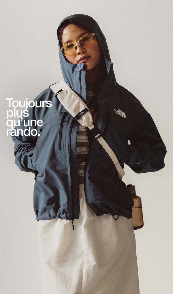 Une femme debout porte un manteau bleu.  