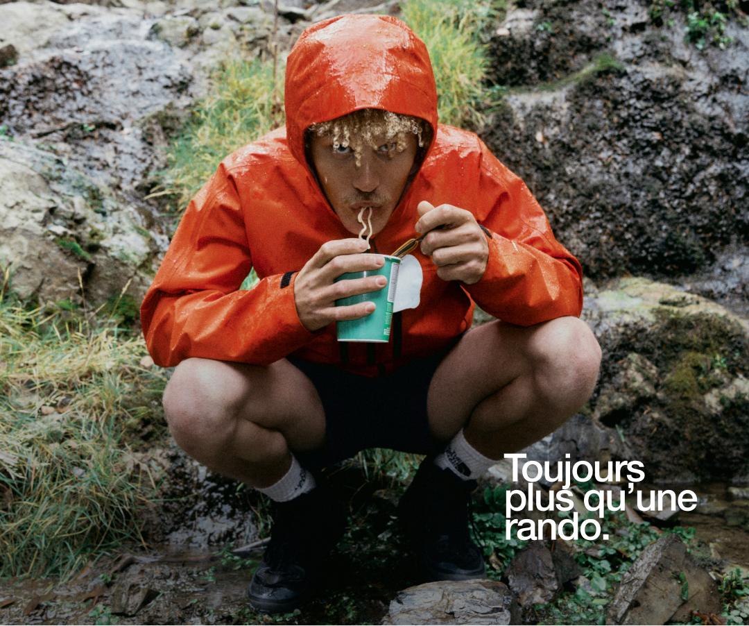 Un homme porte un imperméable rouge sous la pluie.  
