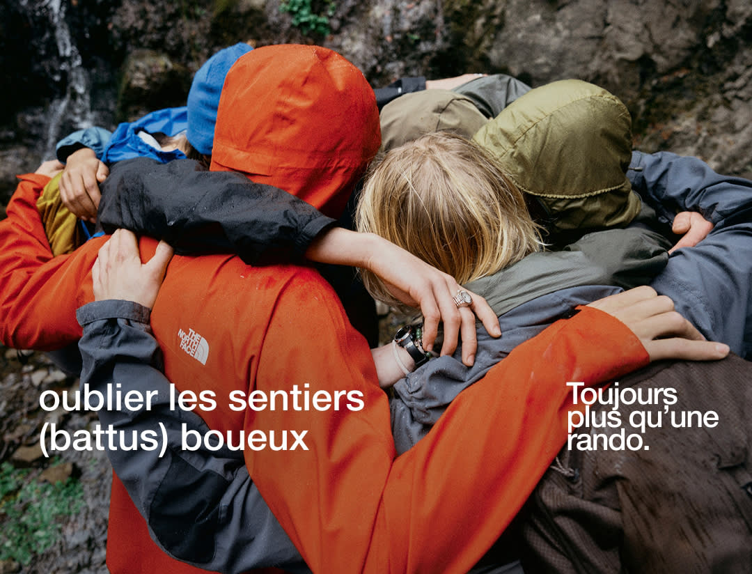 Un groupe de randonneurs en imperméables s'enlaçant.