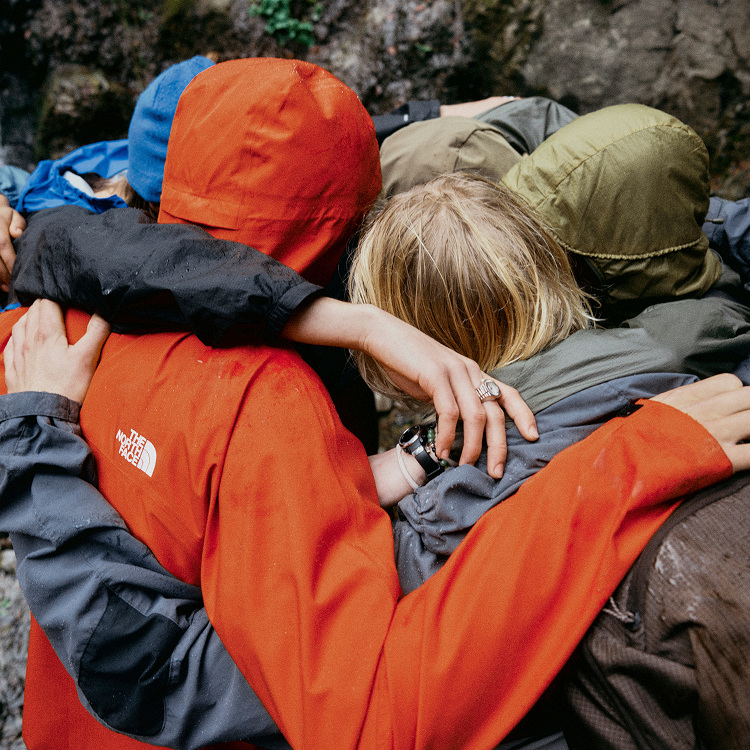 Group hugging in the rain wearing rainwear.