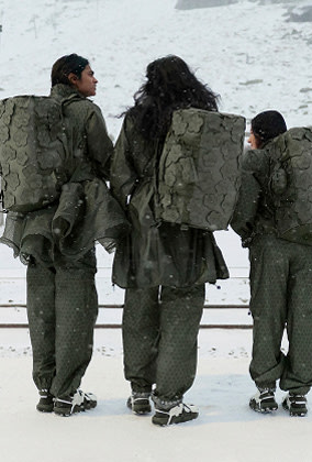 Three models walking through a snowy train station wearing The North Face x Cecilie Bahnsen collection with Anna Base Camp Duffel bags.