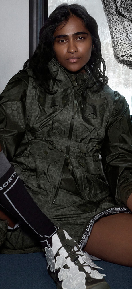 Model in The North Face x Cecilie Bahnsen collection sitting on a train seat wearing the Tenzin Convertible Jacket