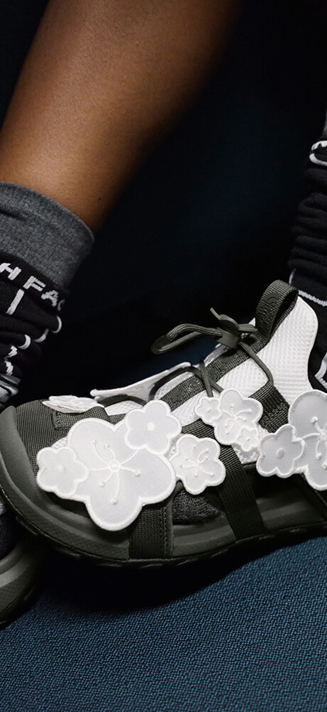 Model in The North Face x Cecilie Bahnsen collection sitting on a train seat wearing the Bekah Sandals