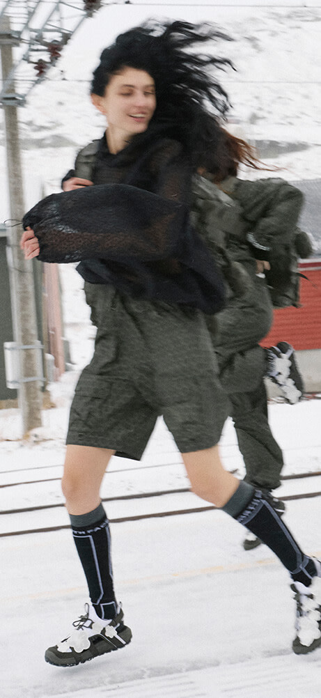 A model running to catch the train wearing The North Face x Cecilie Bahnsen collection with a Anna Base Camp Duffel bag. 