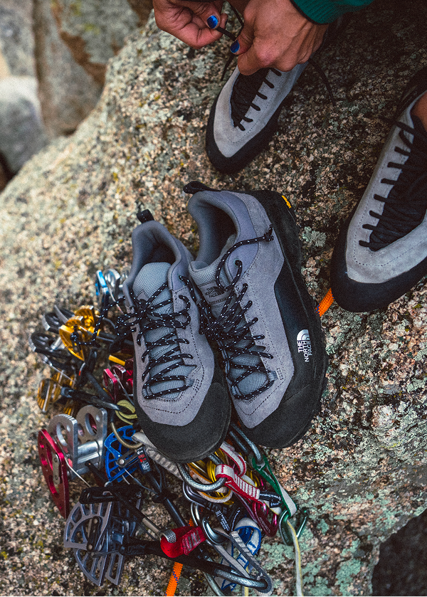 Close up of north face climbing shoes next to climbing gear. 