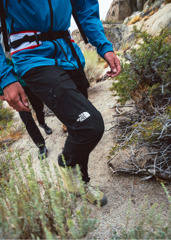 Close up of a person wearing black North Face climbing pants on a trail. 
