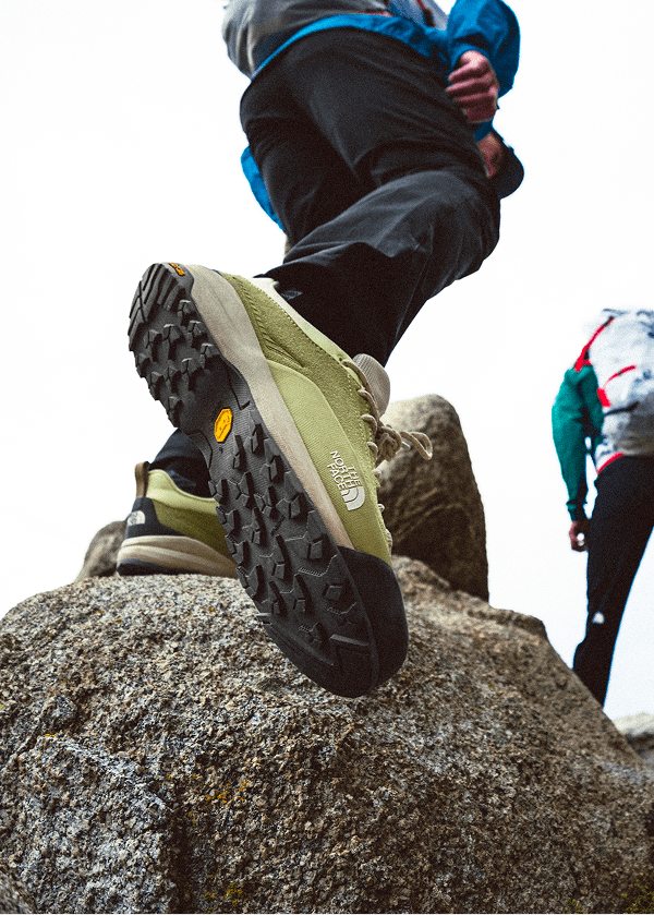 close up shot of a person wearing green North Face climbing shoes
