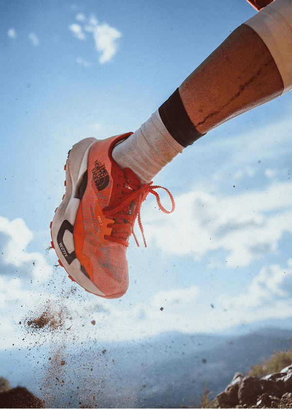 Closeup of a trail run shoe kicking dust behind it. 