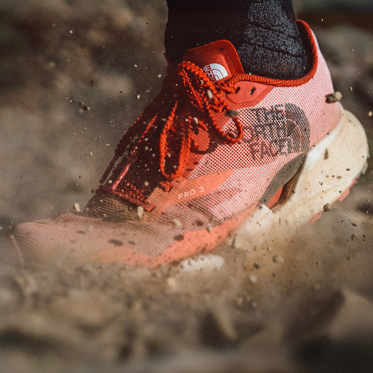 Gros plan sur la chaussure VECTIV™ Pro 3 touchant le sol, avec de la poussière et des débris rocheux projetés en l’air. 