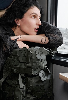 Model gazing out a train window toward alpine mountains in The North Face x Cecilie Bahnsen collection.