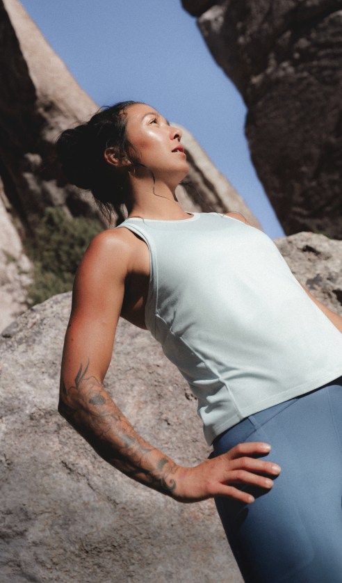 Athlete standing on rocks wearing the Jaida Tank in Opal Frost with the Jaida Pocket Leggings in Granite Grey.