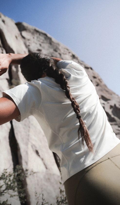 Athlete climbing rock face wearing short-sleeve Jaida Tee and Jaida Pocket Leggings in an outdoor setting.