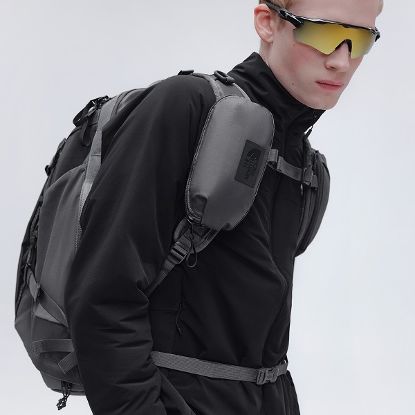 male model wearing the voyager pack looking toward camera with yellow sunglasses on.