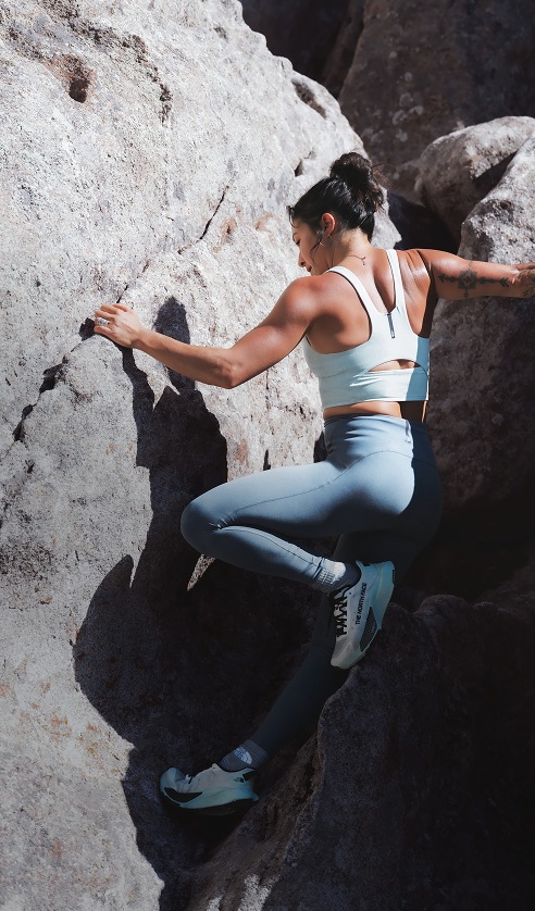 Athlete climbing between rock formations wearing the Jaida Long Line Bra in Opal Frost and Jaida Pocket Leggings in Granite Grey.