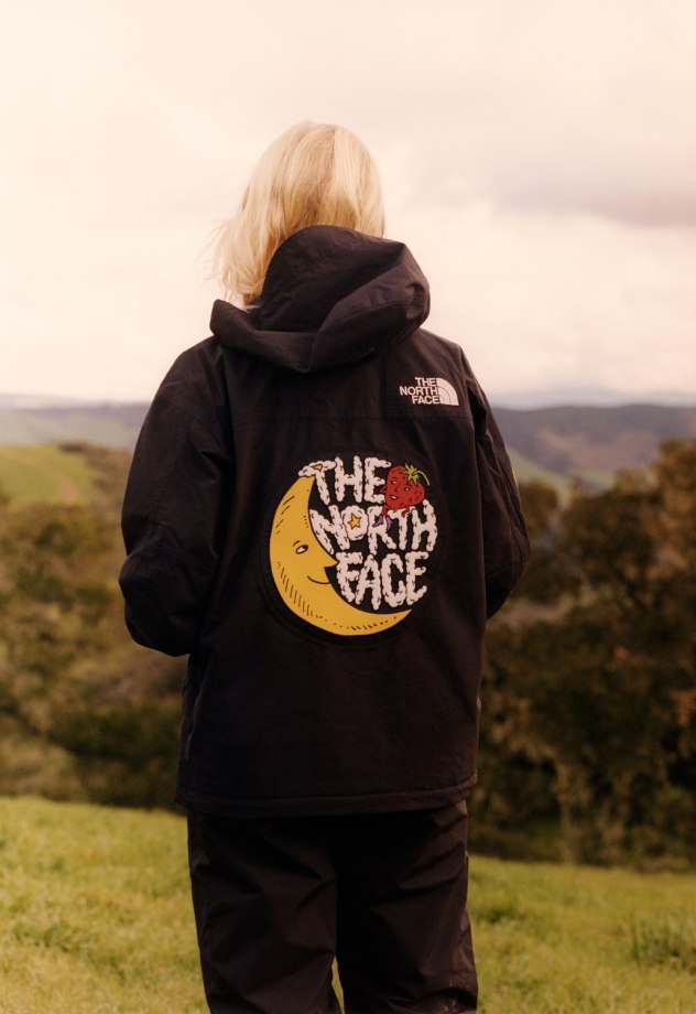 A woman stands on a hill wearing her The North Face Mountain Jacket in collaboration with Sky High Farm Goods.