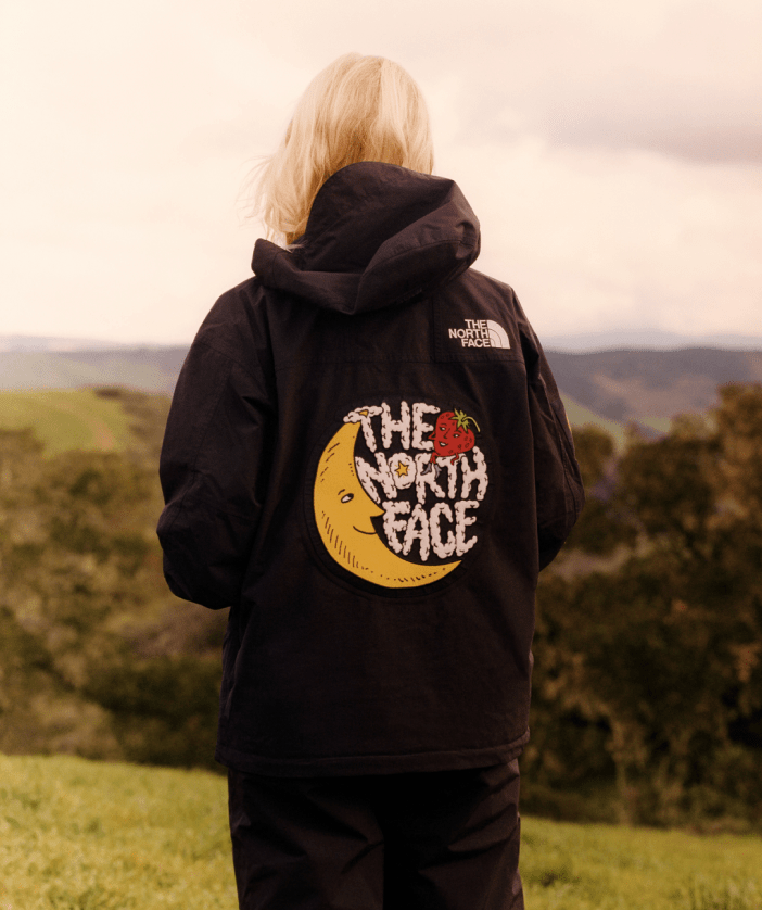 back of a woman wearing The North Face x Sky High Farm Goods Mountain Jacket in a field. 