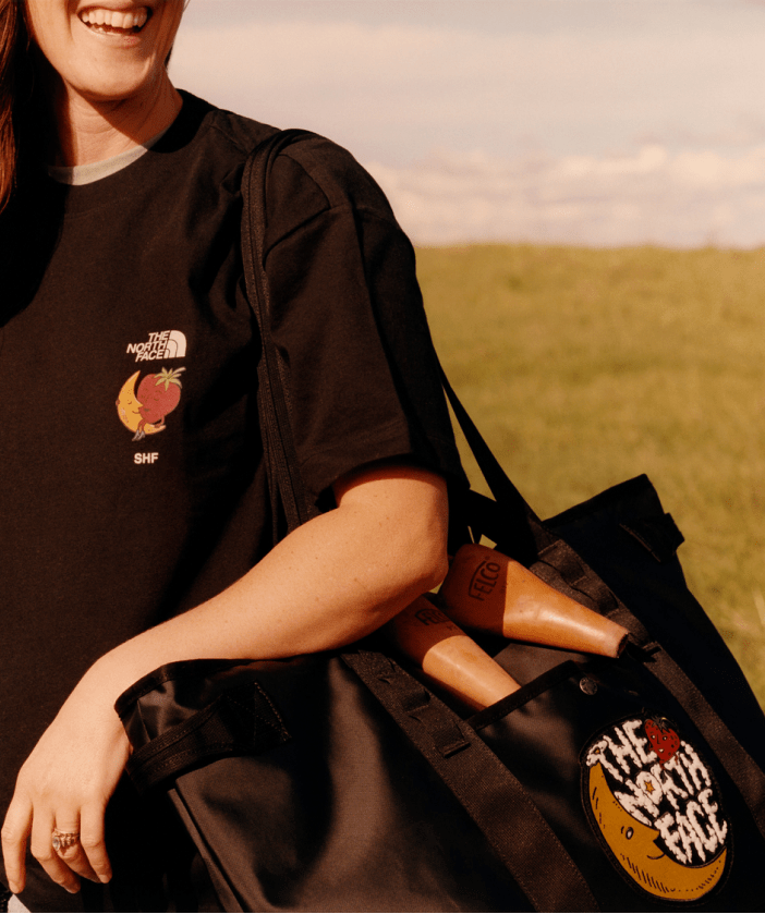 back of a woman wearing The North Face x Sky High Farm Goods Mountain Jacket in a field. 