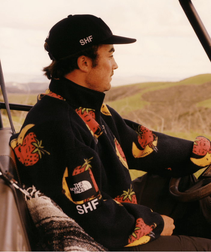 back of a woman wearing The North Face x Sky High Farm Goods Mountain Jacket in a field. 