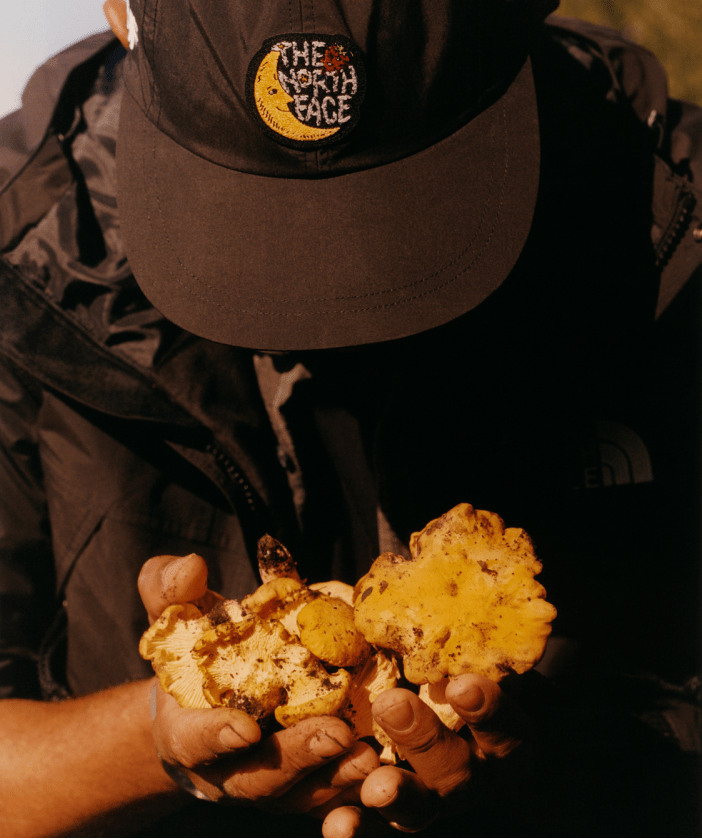 back of a woman wearing The North Face x Sky High Farm Goods Mountain Jacket in a field. 