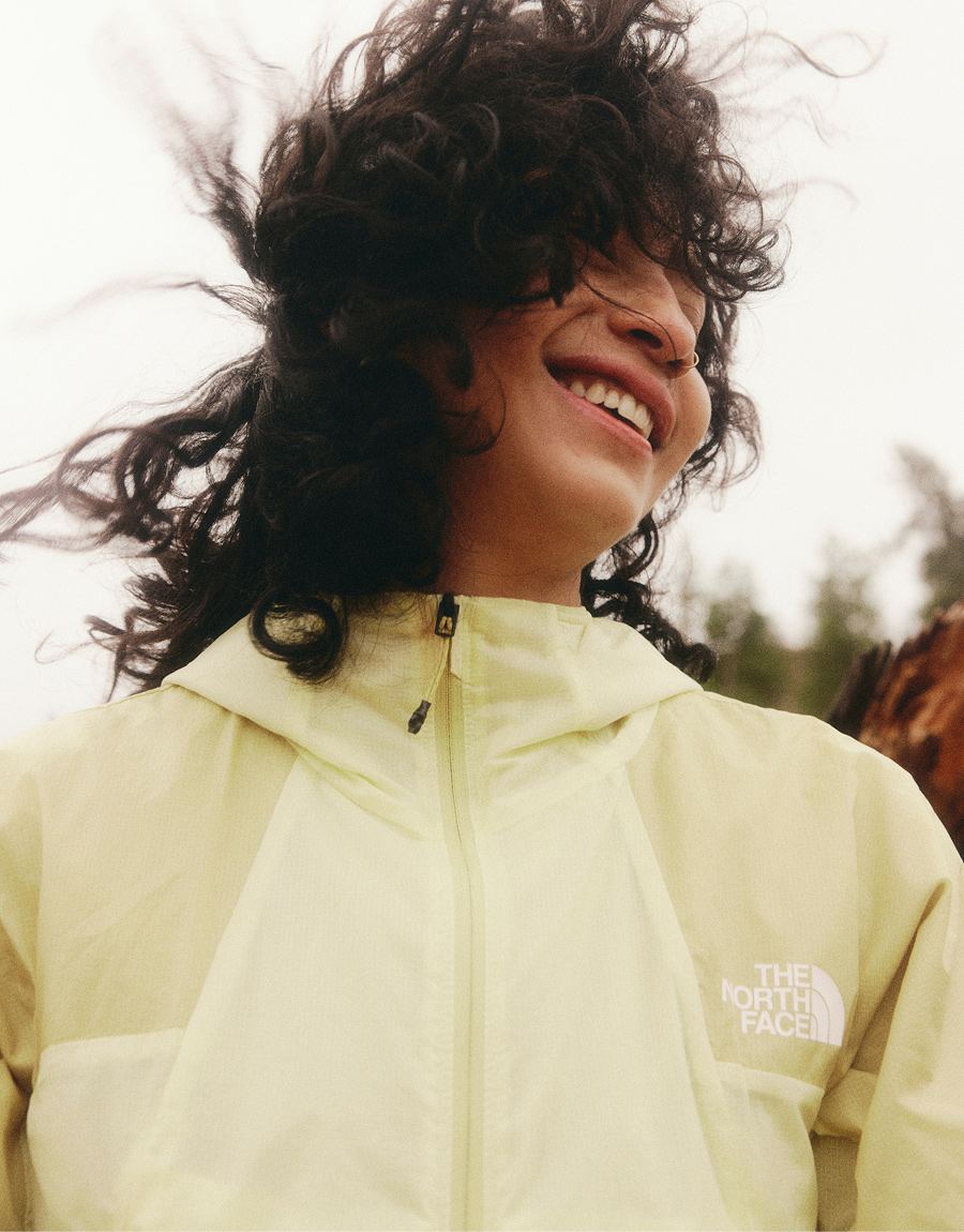 Une personne portant une veste jaune, avec des cheveux foncés et bouclés.