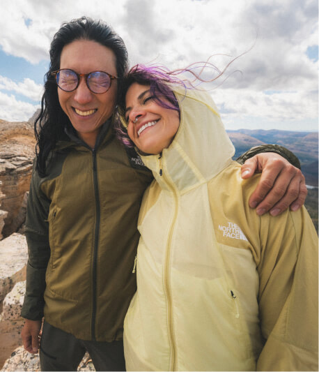 A woman and man smiling wearing wind jackets