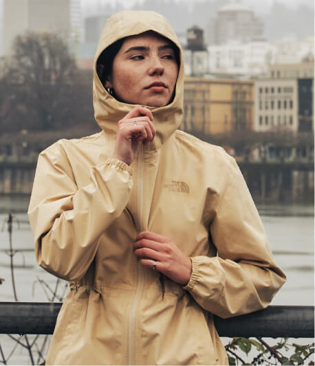 A woman zipping up her yellow rain jacket