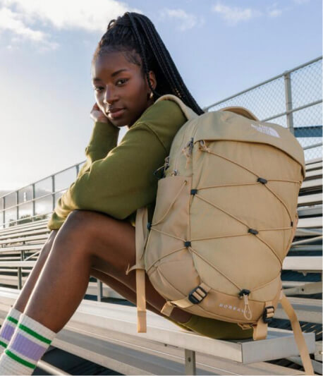 Woman seated on the bleachers with a tan backpack