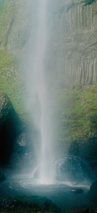Rock wall covered in moss with a waterfall in the middle.