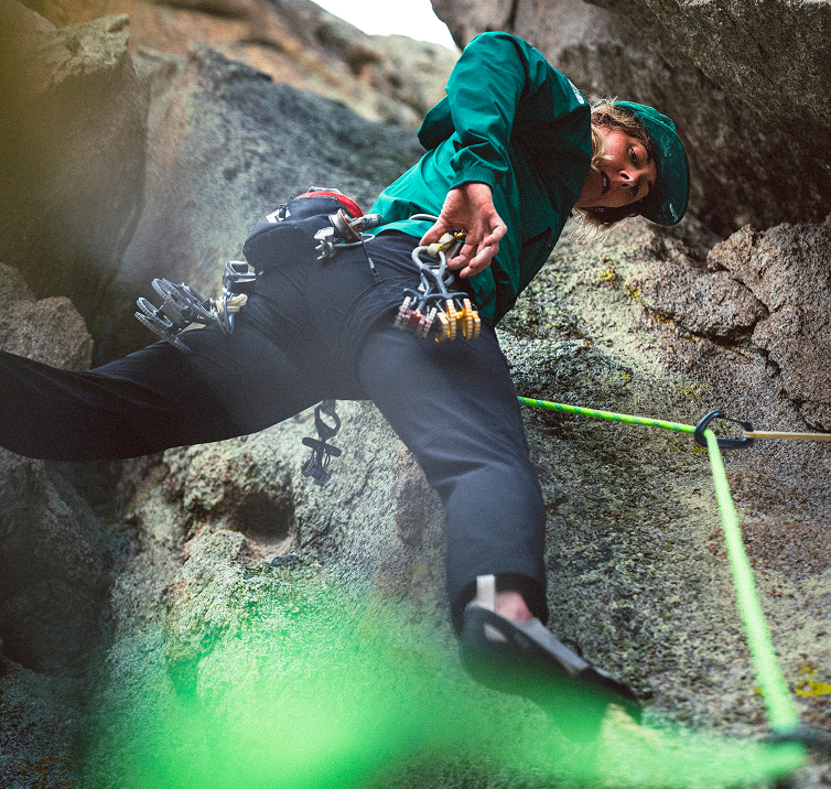 Side view of person in blue jacket climbing up a wall.