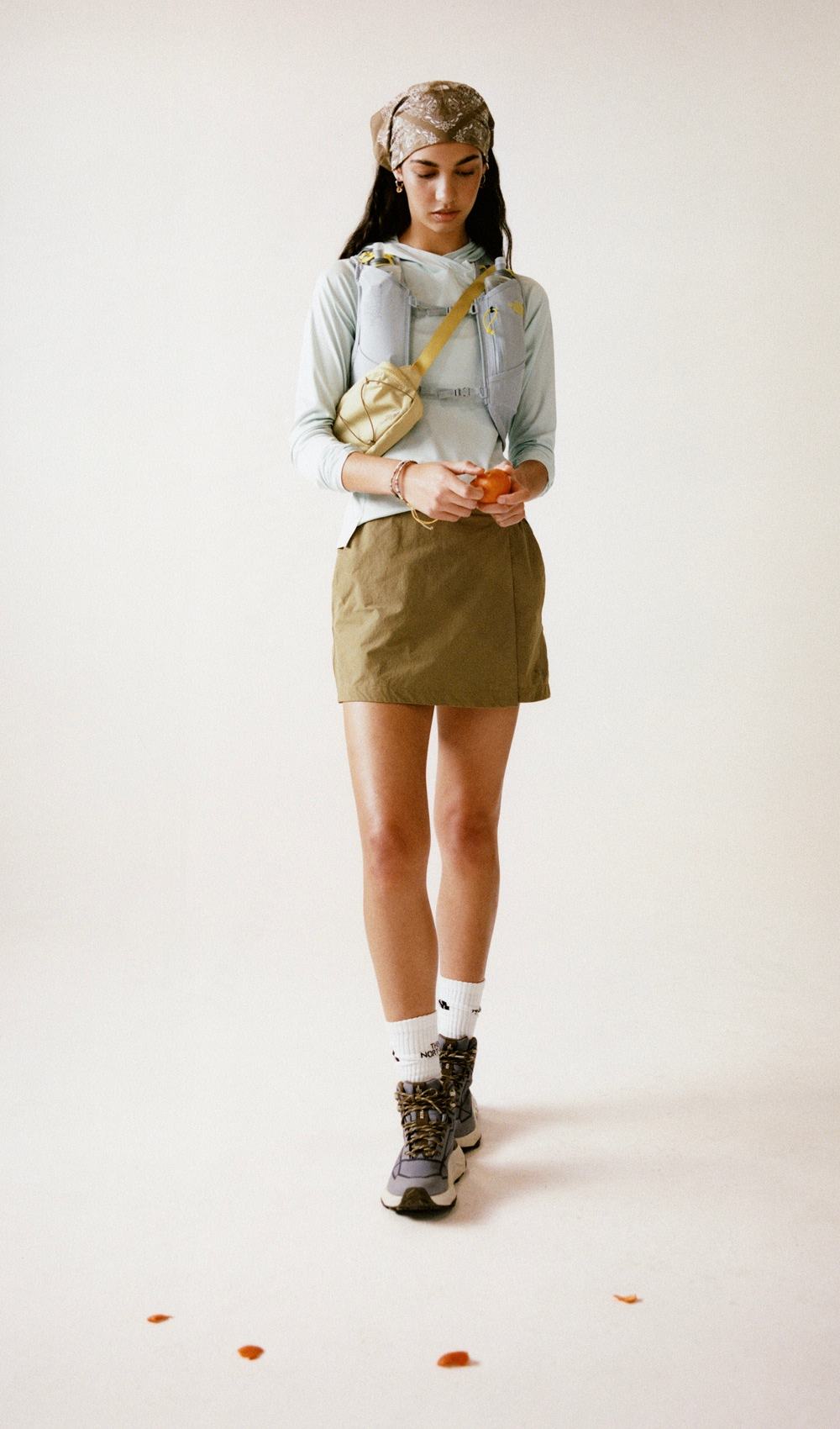A person wearing a blue long sleeve and a brown skirt on a white background