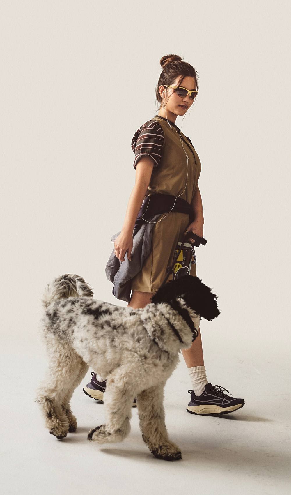 A woman walking her dog wearing a brown dress