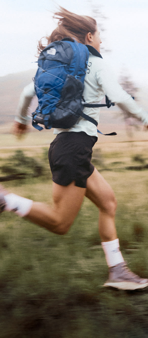 A person in a blue hoodie and shorts is having fun mounting a slackline.