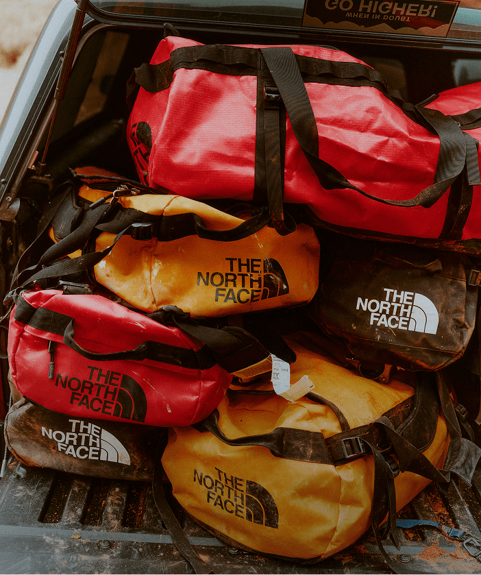 Orange and red duffels piled on top of each other.