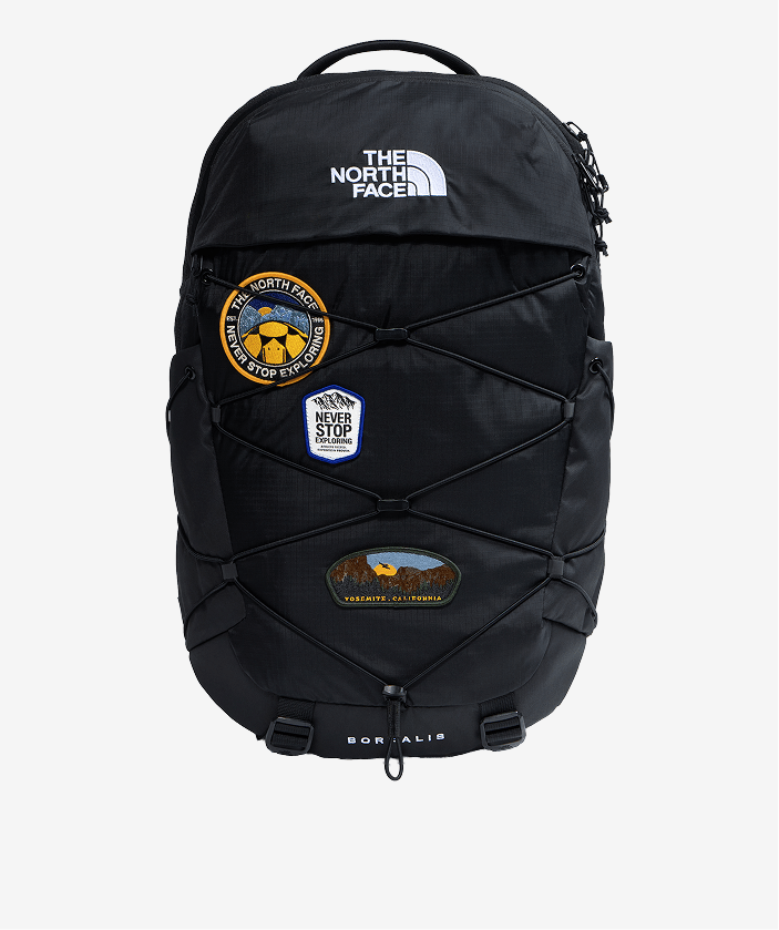 Black Borealis backpack with patches on it on light gray background.