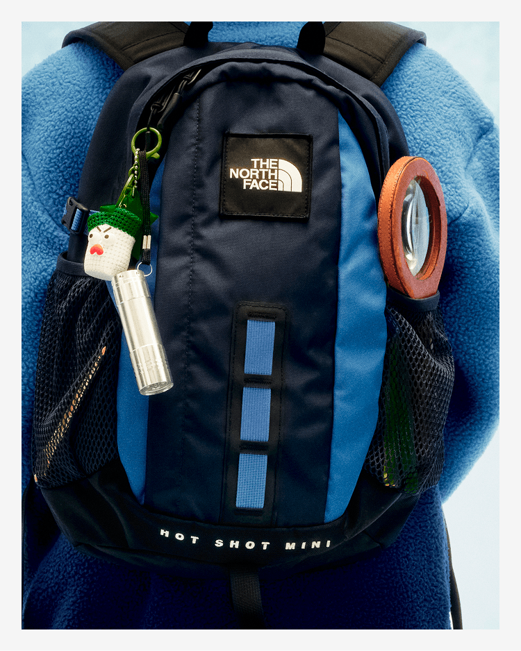 A young person with their back to the camera, wearing a blue and black backpack. 