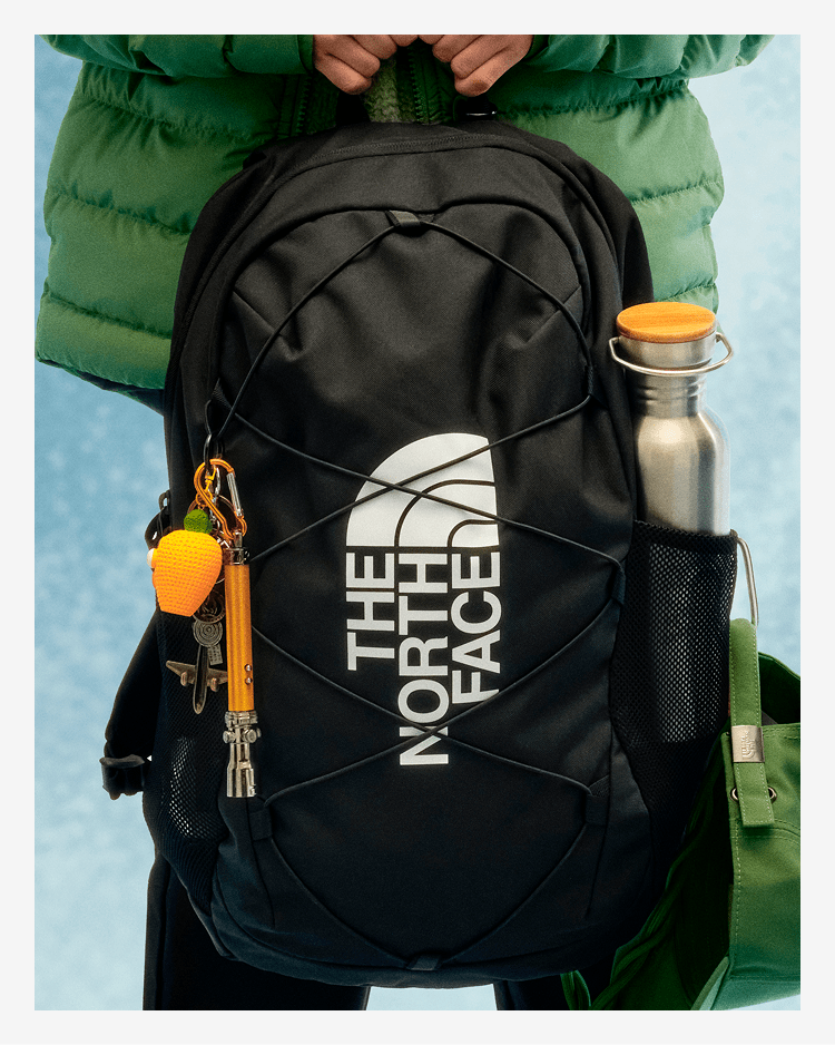 A young person with their back to the camera, wearing a black backpack. 