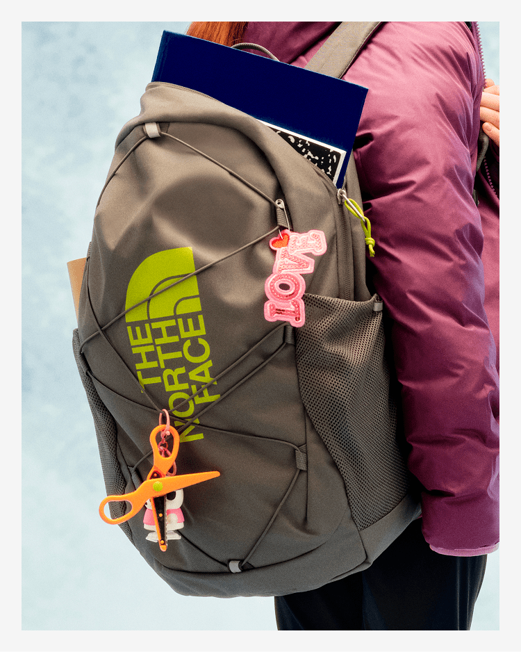 A young person with their back to the camera, wearing a grey backpack. 