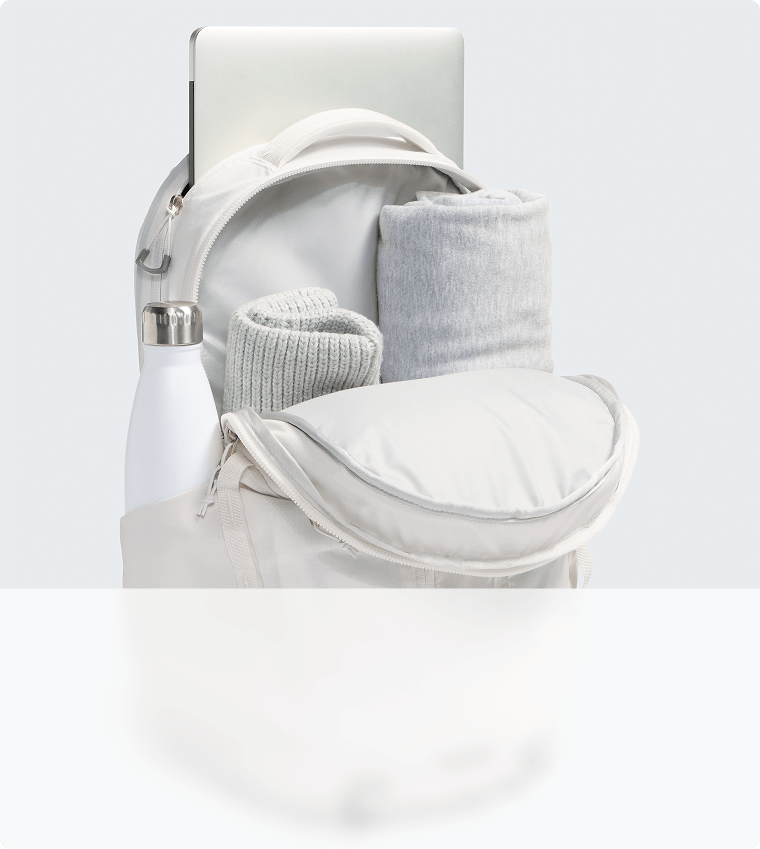 Gros plan sur la capacité de rangement d’un sac à dos blanc. Fermeture à glissière ouverte, compartiment principal visible.