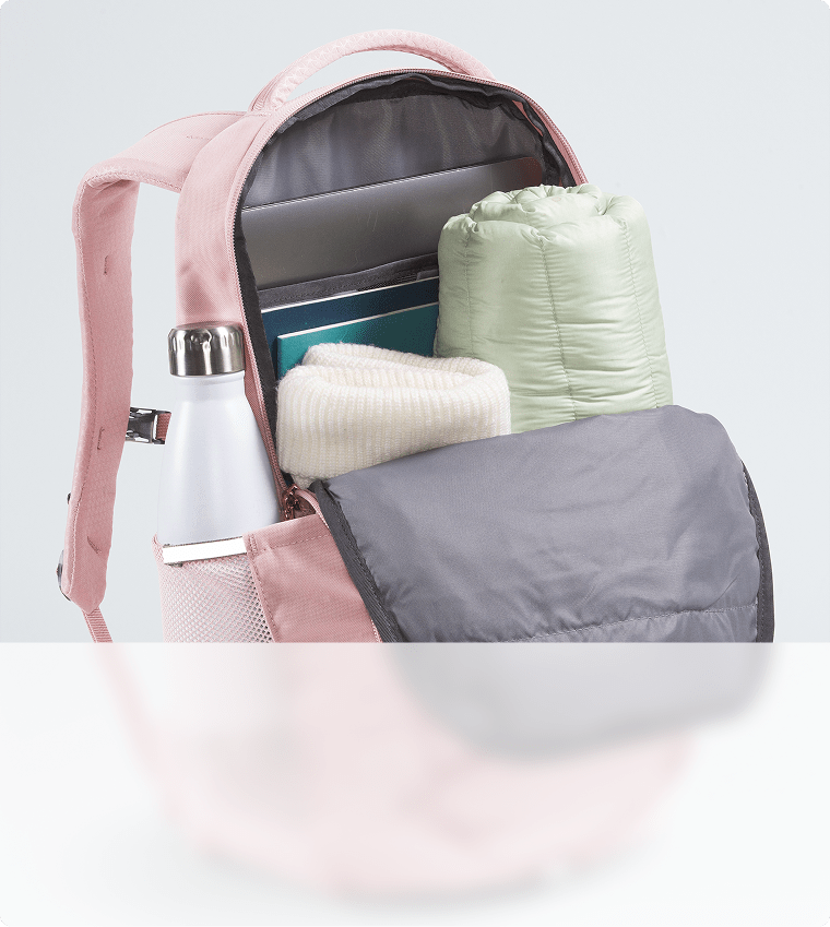 Gros plan sur la capacité de rangement d’un sac à dos rose. Fermeture à glissière ouverte, compartiment principal visible.