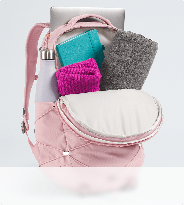 Gros plan sur la capacité de rangement d’un sac à dos rose. Fermeture à glissière ouverte, compartiment principal visible.  